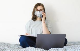 fille à lunettes et un masque. résout les problèmes de travail, signe des documents. photo