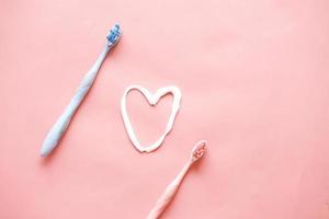 brosse à dents et pâte sur fond rose photo