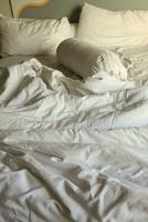 désordonné Hôtel lit. blanc oreiller. blanc rouleau. blanc couverture. photo