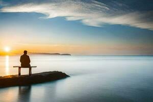 une homme est assis sur une banc surplombant le océan à le coucher du soleil. généré par ai photo