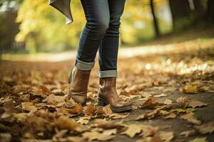 femme dans jeans et bottes en marchant sur l'automne parc. fermer de le pieds. l'automne mode concept, l'automne s'orienter. génératif ai photo