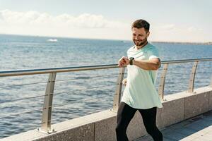 une homme formation aptitude dans une confortable T-shirt. une entraîneur avec des lunettes Est-ce que une fonctionnement exercice chaque jour, une en bonne santé mode de vie. une sportif la personne les usages une aptitude regarder et une fonctionnement application. photo