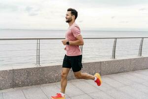 le fonctionnement entraîneur est une homme et les trains en plein air. coureur athlète dans aptitude vêtements et fonctionnement chaussures, toute la longueur. les usages une aptitude regarder pour une fort la personne et des sports pour santé. photo