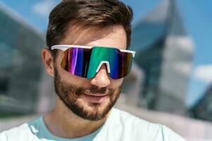 portrait de une homme dans aptitude des sports lunettes. le athlète est une gars avec une barbe. photo