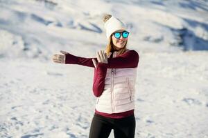 content femme dans chaud vêtements exercice bras sur neigeux plaine photo