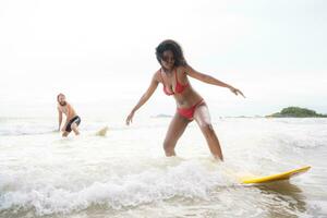 couple surfant sur le plage ayant amusement et équilibrage sur le planche de surf photo