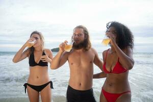 Multi-éthnique groupe de copains ayant amusement sur le plage, en buvant Bière et ayant amusement photo