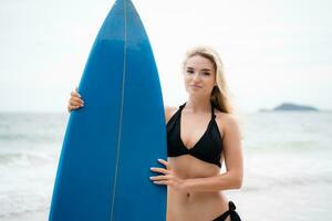 surfeur fille avec sa planche de surf sur le plage. photo