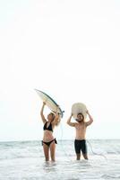 Jeune homme et femme en portant planches de surf sur leur têtes et marcher dans le mer à le surf photo
