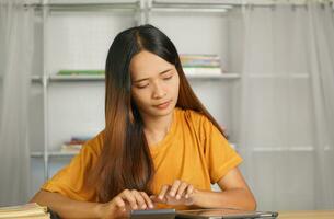 asiatique femmes presse à travail de Accueil Cliquez sur sur le calculatrice à voir bénéfices. photo