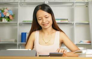 asiatique femmes presse à travail de Accueil Cliquez sur sur le calculatrice à voir bénéfices. photo