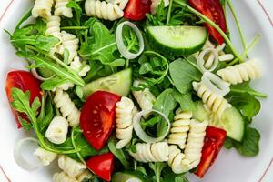 Pâtes salade fusilli Pâtes, concombre, tomate, vert laitue, oignon en bonne santé en mangeant cuisine apéritif repas nourriture casse-croûte sur le table copie espace nourriture Contexte rustique Haut vue photo