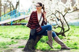 ensoleillé printemps portrait de content Jeune femme en riant et posant près fleur arbre. photo