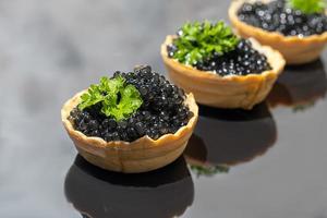 caviar noir en tartelettes sur fond sombre. concept d'alimentation saine. photo