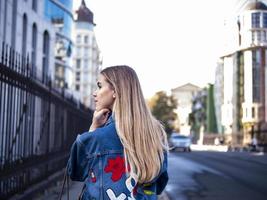 jolie blonde aux cheveux flottants dans une veste en jean sur le pont en plein air photo