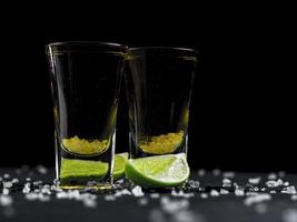 deux shots de tequila gold avec du citron vert juteux et du sel de mer