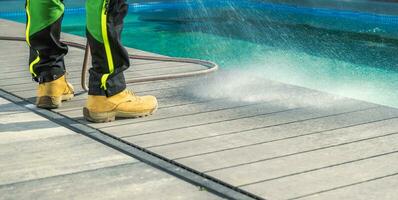 homme nettoyage le sien au bord de la piscine plate-forme avec une l'eau photo