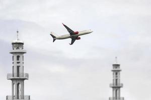 un avion survolant deux minarets d'une mosquée photo