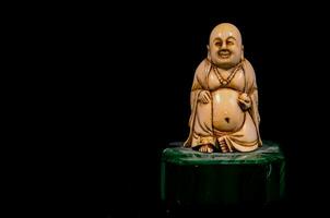 une petit statue de une Bouddha séance sur une vert marbre base photo