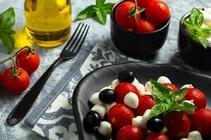 classique italien salade caprese servi dans original forme avec Cerise tomates, mini Mozarella perles, basilic feuilles et balsamique glaçage photo