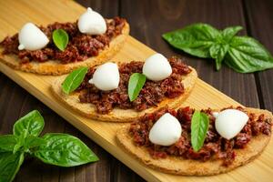 bruschetta aux tomates séchées, mozzarella, ail et huile d'olive. sandwich de cuisine italienne traditionnelle à base de ciabatta grillée. antipasti photo