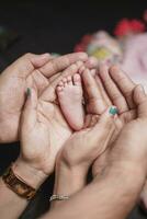 le petit jambes de une nouveau née bébé dans le mains de le sien maman et père. le concept de maternité et enfance photo