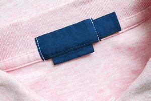 Vide bleu blanchisserie se soucier vêtements étiquette sur rose chemise en tissu texture Contexte photo
