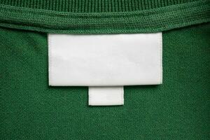 Vide blanc blanchisserie se soucier vêtements étiquette sur vert chemise en tissu texture Contexte photo