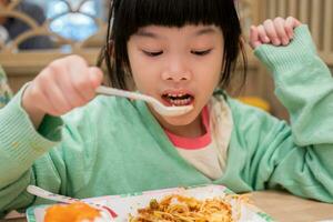 mignonne peu asiatique enfant fille en mangeant nourriture photo