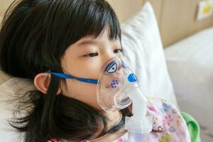malade peu asiatique fille inhalation avec nébuliseur pour respiratoire traitement photo