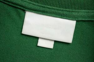 Vide blanc blanchisserie se soucier vêtements étiquette sur vert chemise en tissu texture Contexte photo