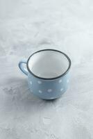 vide petit bleu et blanc polka point café tasse sur gris rustique Contexte. rétro style céramique pour chaud breuvages. fermer, copie espace photo