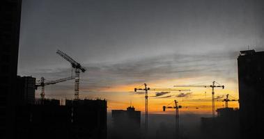construction de bâtiments avec des grues au coucher du soleil photo