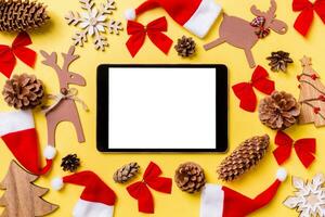 fond jaune de noël avec des jouets et des décorations de vacances. vue de dessus de la tablette numérique. concept de bonne année photo