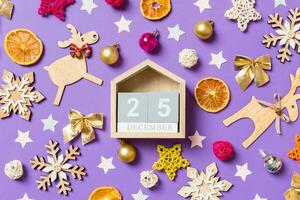 vue de dessus du calendrier en bois entouré de jouets et de décorations du nouvel an sur fond violet. le vingt cinq décembre. notion de temps de noël photo