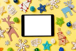 Haut vue de numérique tablette sur Jaune Contexte avec Nouveau année jouets et décorations. Noël temps concept photo