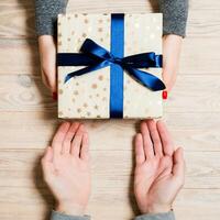 Haut vue de donnant et recevoir une présent sur en bois Contexte. une homme et une femme en portant cadeau dans mains. proche en haut de de fête concept photo