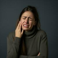 femme apparaît à être dans douleur sur gris Contexte ai génératif photo