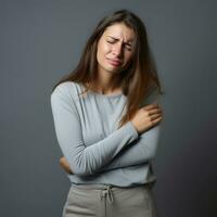 femme apparaît à être dans douleur sur gris Contexte ai génératif photo