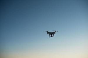 un drone blanc vole dans le ciel en enregistrant une vidéo photo