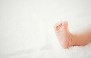 jambes de bébé nouveau-né sur un lit blanc. photo