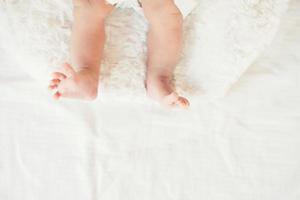 jambes de bébé nouveau-né sur un lit blanc. photo