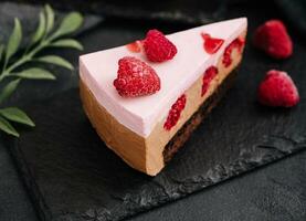 pièces de cheesecake avec framboises sur noir planche photo