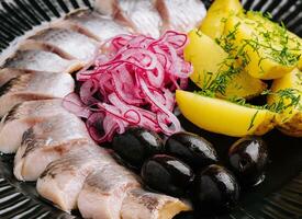 proche en haut de savoureux mariné hareng avec patates et oignons dans assiette photo