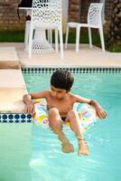 content Indien garçon nager dans une piscine, enfant portant nager costume le long de avec air tube pendant chaud été les vacances, les enfants garçon dans gros nager bassin. photo