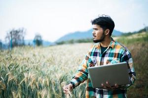 agriculteur intelligent vérifiant la ferme d'orge avec un ordinateur portable photo