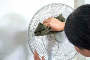 proche en haut main toucher chiffon sale et poussière sur sol ventilateur. mauvais pour la santé air couler. essuyer, frotter et laver, horizontal photo de main nettoyage sale ventilateur lame avec chiffon.