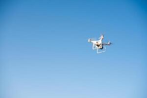 un drone blanc vole dans le ciel en enregistrant une vidéo photo