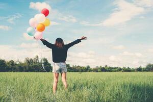 Dos d'une jeune femme heureuse debout sur un champ vert, profitez de l'air frais photo