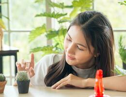 portrait jardin magnifique jolie Jeune asiatique femme portant blanc chemisier avec longue noir cheveux et sourire Frais content se détendre brillant sourire Regardez main en portant pot petit arbre vert Feuille plante dans pièce magasin photo